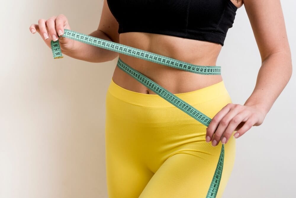 Woman with measurement tape and flat stomach.